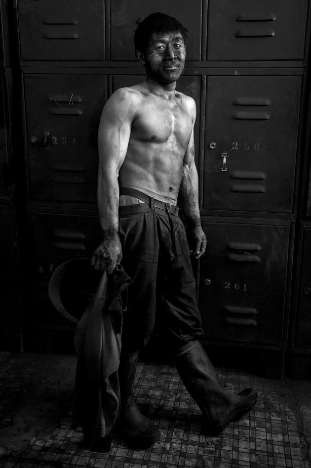 A coal miner rests in a change room at the end of his shift in an underground mine. Parts of his body are covered in coal dust; it was ingrained in his clothes, hands and face. There were also tiny bits of coal embedded in his lips. Xingyu, Yunnan &ndash; China. Image &copy; Michael Coyne.