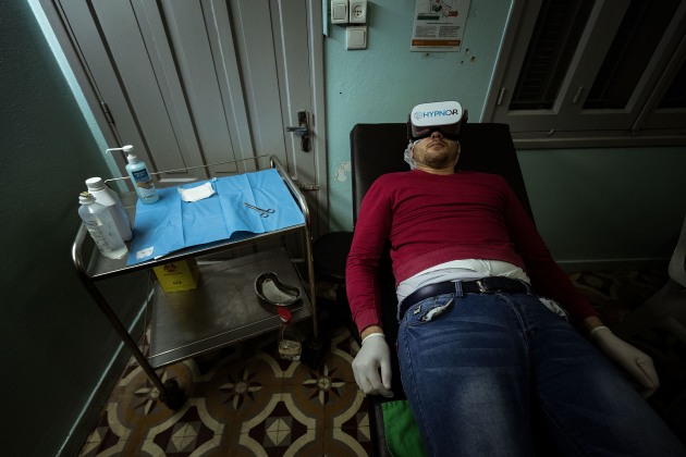 &copy; Darrian Traynor, from the series, 'More than skin deep'. GAZA. 3rd March 2020. He has severe nerve damage in his lower leg. It will take many years to recover with nerves growing at only 1cm per year. He is still very angry and becomes very agitated when talking. Despite initial counselling offered through MSF, Mohammed has given up on pursuing metal health support as his frustration at his physical recovery grows. Here Mohammed is using virtual reality goggles to distract him from the pain during his therapy.