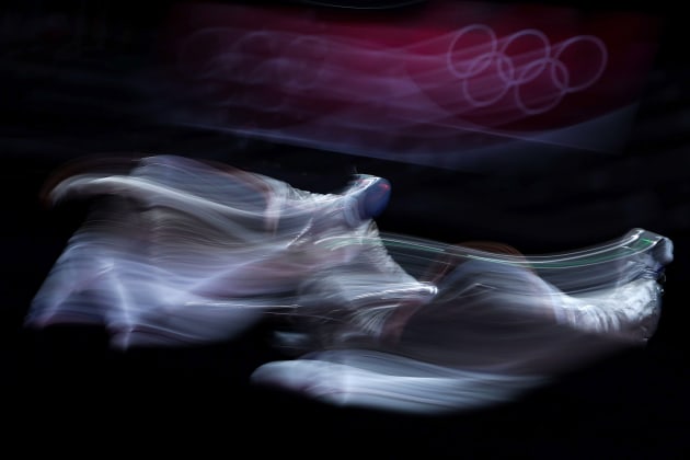 Patrick Smith/Getty Images, Fencing - Olympics Day: 6. “In this photo, Getty Images Staff Photographer Patrick Smith used a slow shutter speed to capture the movement and action of a fencers Luigi Samele of Team Italy and Aron Szilagyi of Team Hungary competing on day five of the Tokyo 2020 Olympic Games. His framing of the Olympics rings in the background gives the photo a sense of time and place. Technically this type of photo is very difficult to make as you need to have something in the frame that is in focus, which at a slow shutter speed, is very hard to achieve.