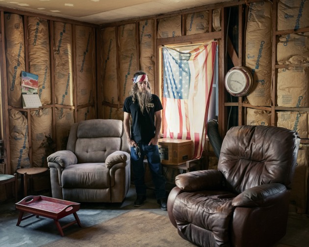© Adam Ferguson. Jody Marquess (42) stands for a portrait in the home of his deceased stepfather in Phoenix, Arizona, on 23 June, 2021. His stepfather, John Ramer (69), died 17 June during a heatwave in Phoenix on Jody’s birthday. “He had tough-guy syndrome and was very frugal. He was an honest and simple man,” said Jody. Jody said the temperature inside the house was 130°F. “He was cooking in a leather chair.”